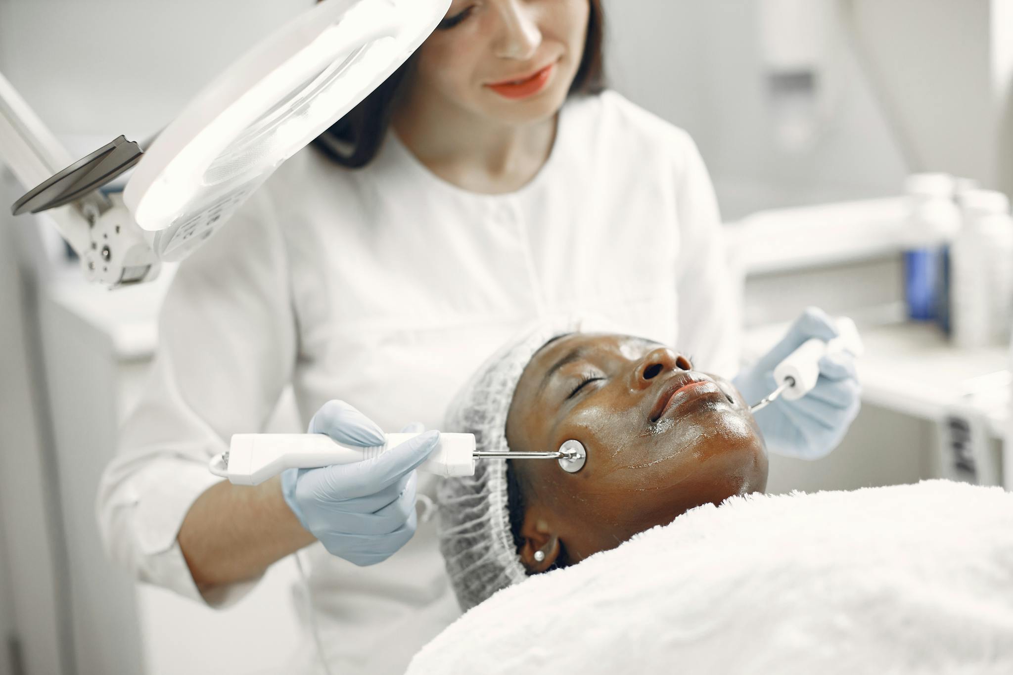 Dermatologist performing facial treatment on a relaxed patient in a modern clinic setting.